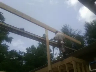 Carpenter setting a ridge beam over a new addition frame — Ice Dam Removal by Roofing Brothers in Conneaut