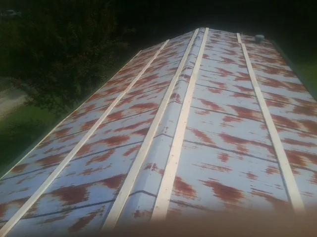 Rusted metal roof panels with new wood purlins before replacement — Storm Damage Roof Repair in Conneaut by Roofing Brothers
