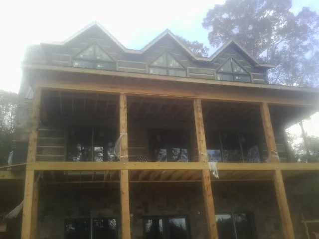 Dormers and porch framing on a large log home under construction — Roof Coating work by our crew in Conneaut