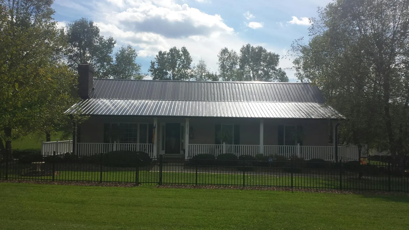 Gray metal roof on a brick ranch with a full width front porch — Gutter Guard Installation work by our crew in Conneaut