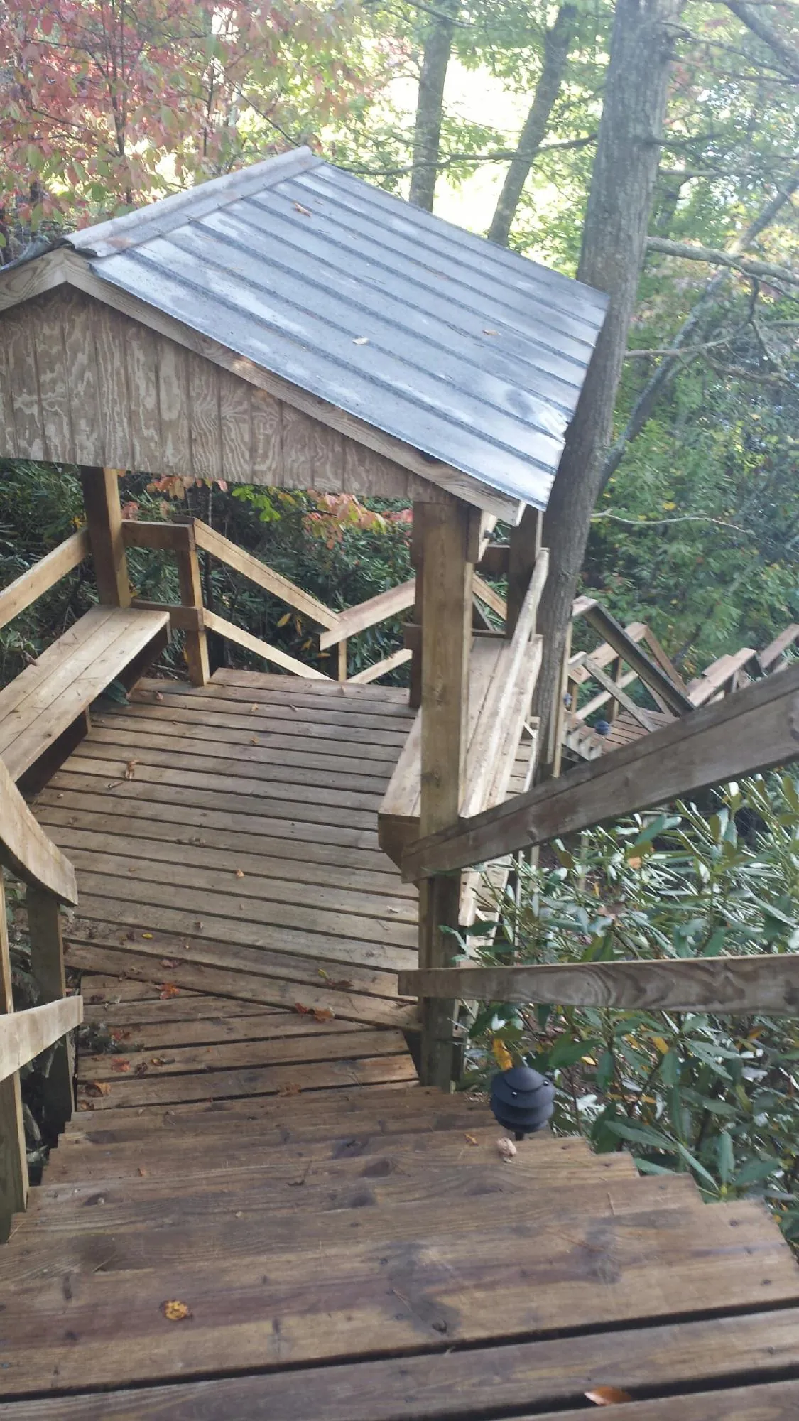 Metal roofed shelter over wooden steps on a wooded walkway — Skylight Repair & Installation work by our crew in Conneaut
